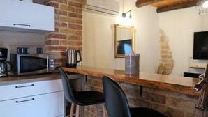 Eine Küche mit Mikrowelle, Kaffeemaschine, Wasserkocher und einer Bar mit zwei Sesseln.