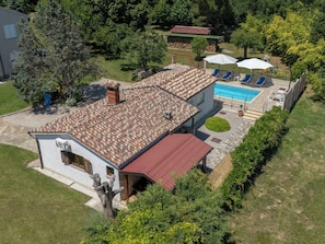 Um imóvel residencial com piscina, um pátio com espreguiçadeiras e um jardim.