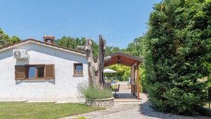 A white building with a pergola, a large evergreen tree, and a gravel pathway. - Verbanac by Interhome (Labin)