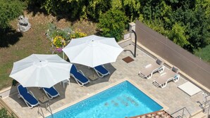 A rooftop pool area with blue lounge chairs and white umbrellas, surrounded by greenery. - Verbanac by Interhome (Labin)