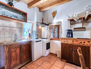 A kitchen with wooden cabinets, a stove, a microwave, and a coffee maker.