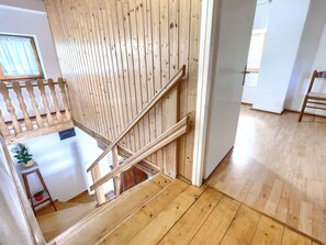 A wooden staircase leading to an upper floor with a view of a room below.