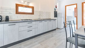 A modern kitchen with grey cabinets, a built-in stove, and a window above the sink. - Il Melograno by Interhome (Capoliveri)