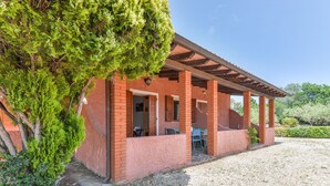A covered outdoor area with brick walls, a pergola, and a gravel ground.