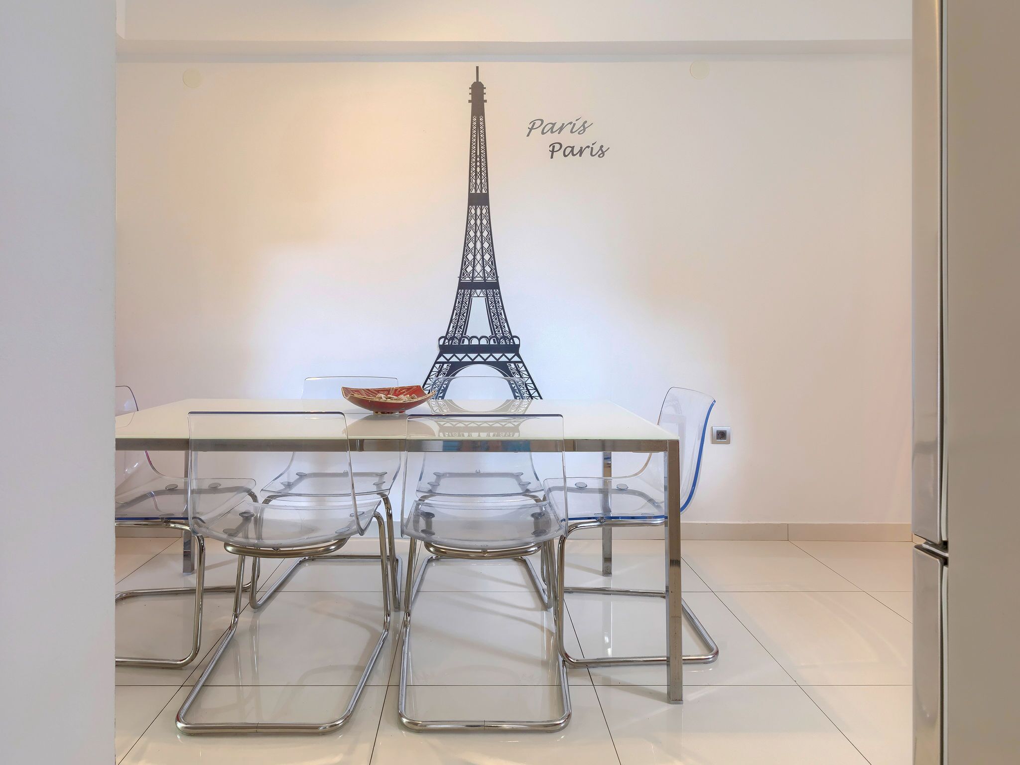 Uma área de refeições com mesa, cadeiras e uma réplica decorativa da Torre Eiffel.