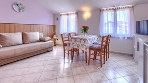 Ein gemütliches Wohnzimmer mit einer Couch, einem Esstisch, Stühlen und einem Fernseher.