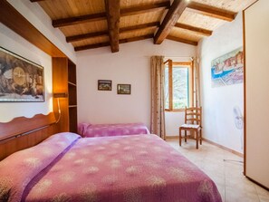 Ein Zimmer mit zwei Betten, einer Holzbalkendecke, einem Fenster mit Vorhängen und einem Bild an der Wand.