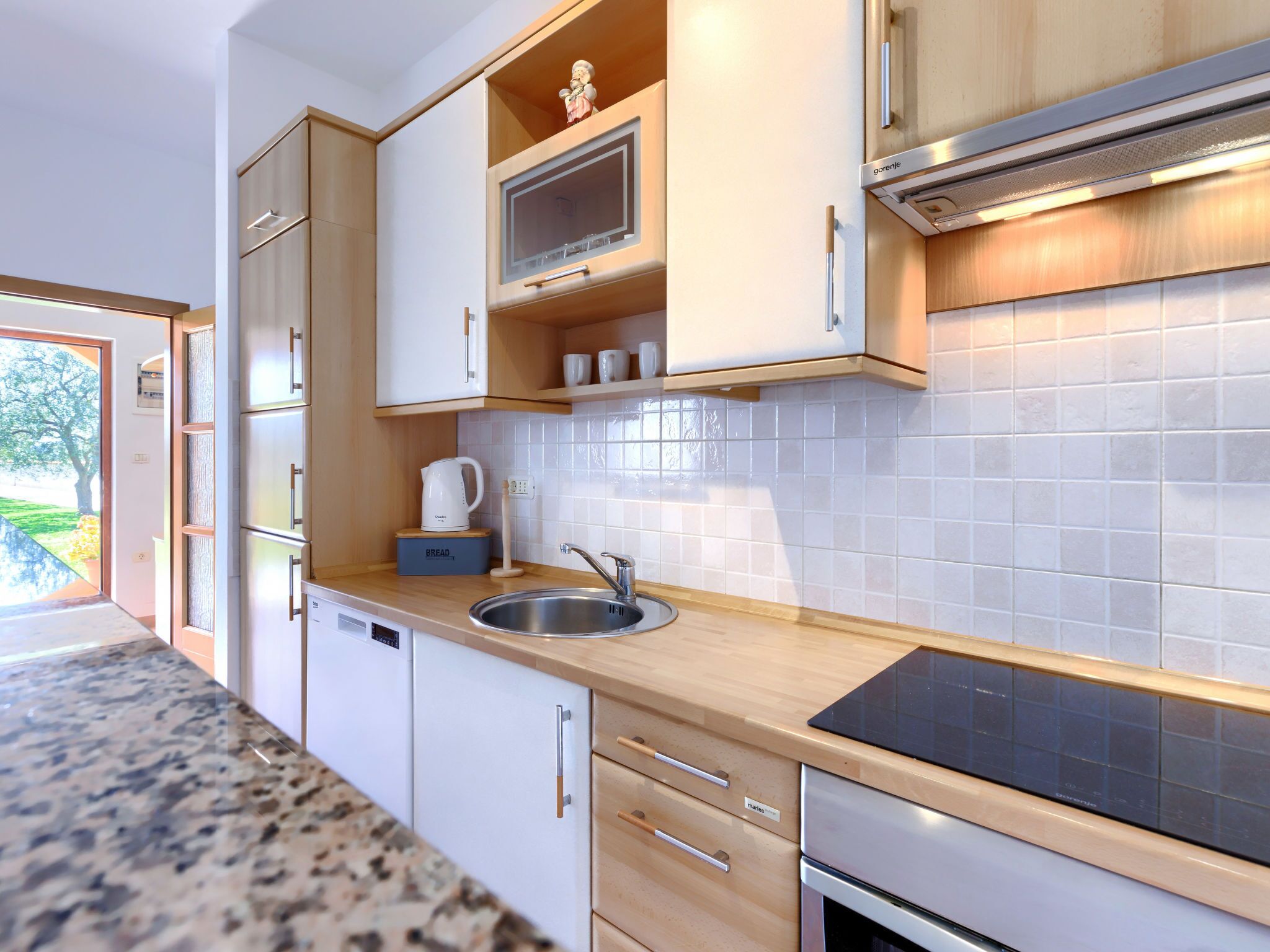 Een moderne keuken met houten kastjes, een roestvrijstalen spoelbak en een ingebouwde magnetron.