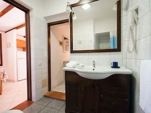 A bathroom with a white sink, dark wooden cabinet, and a mirror above it.