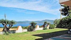 Eine Terrasse mit Pingpongtisch, Rasenfläche und Blick auf das Meer und die Hügel.