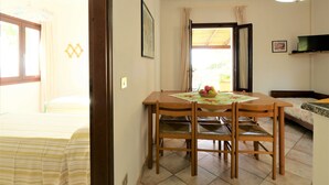 Une pièce comprenant une table à manger en bois, des chaises, un téléviseur et un lit.