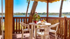Une terrasse en bois avec une table et des chaises donnant sur un lac.