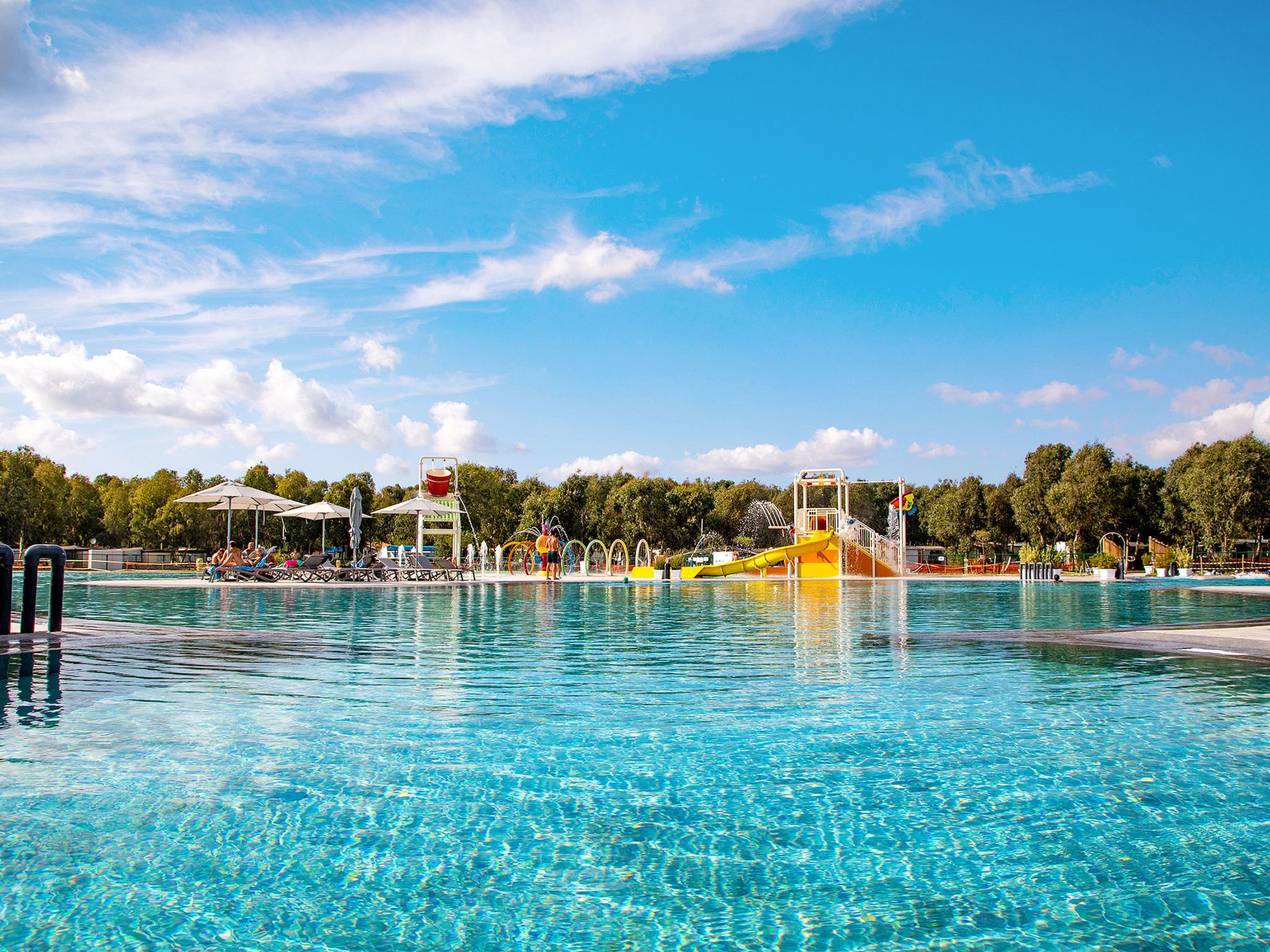 A swimming pool with a water slide and lounge chairs.