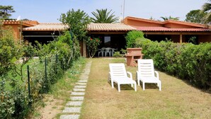 A patio area with two white lounge chairs, a stone pathway, and a small table. - Rei Marina Fronte Mare (REI204) by Interhome (Costa Rei)
