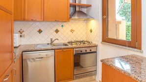 A compact kitchen with wooden cabinets, a Bosch dishwasher, a gas stove, and a stainless steel oven. - Rei Sole (REI303) by Interhome (Costa Rei)