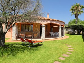 A house with a stone facade, a patio with outdoor furniture, and a well-maintained lawn.
