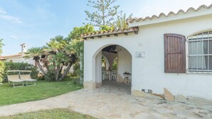 A white building with a stone pathway leading to an archway. There is a table and chairs outside the archway. - Gigli (REI226) by Interhome (Costa Rei)