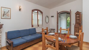 A dining area with a wooden table set for four, a blue sofa, and a wooden cabinet. - Gigli (REI226) by Interhome (Costa Rei)