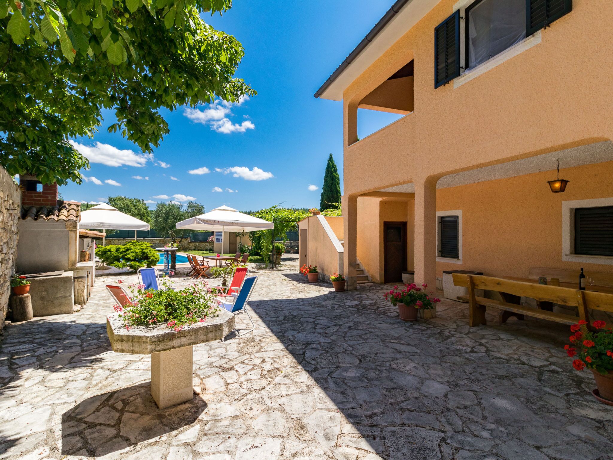 A courtyard with stone flooring, outdoor seating, and a pool.