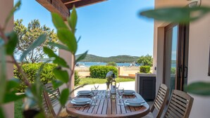 Una mesa de madera preparada para comer, con vistas al mar y las colinas.