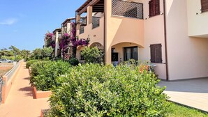 Una hilera de edificios de estilo mediterráneo con balcones, arcos y abundante vegetación.