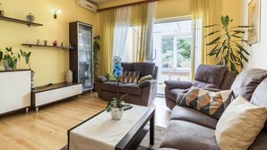 Ein Wohnzimmer mit einer Sofagarnitur, einem Couchtisch, einem Schrank und einer großen Pflanze.