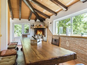 Un'area pranzo rustica con un grande tavolo di legno, panche e una parete in mattoni.
