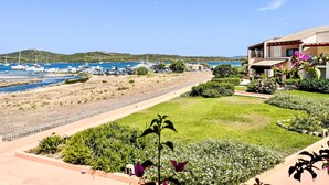 A coastal property with a marina, a well-maintained lawn, and a two-story building with a tiled roof.