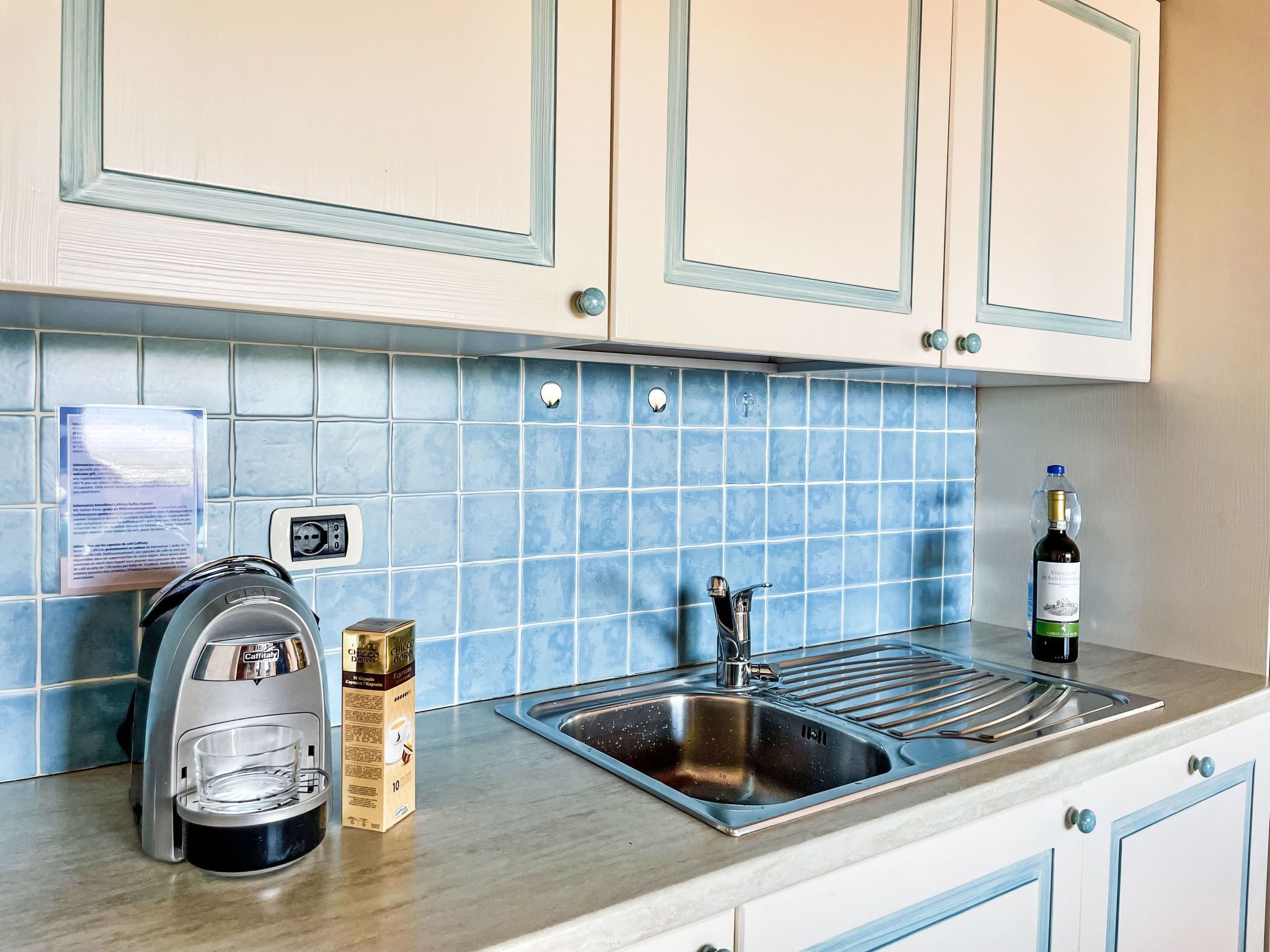 A kitchen with a coffee maker, a bottle of wine, and a sink.