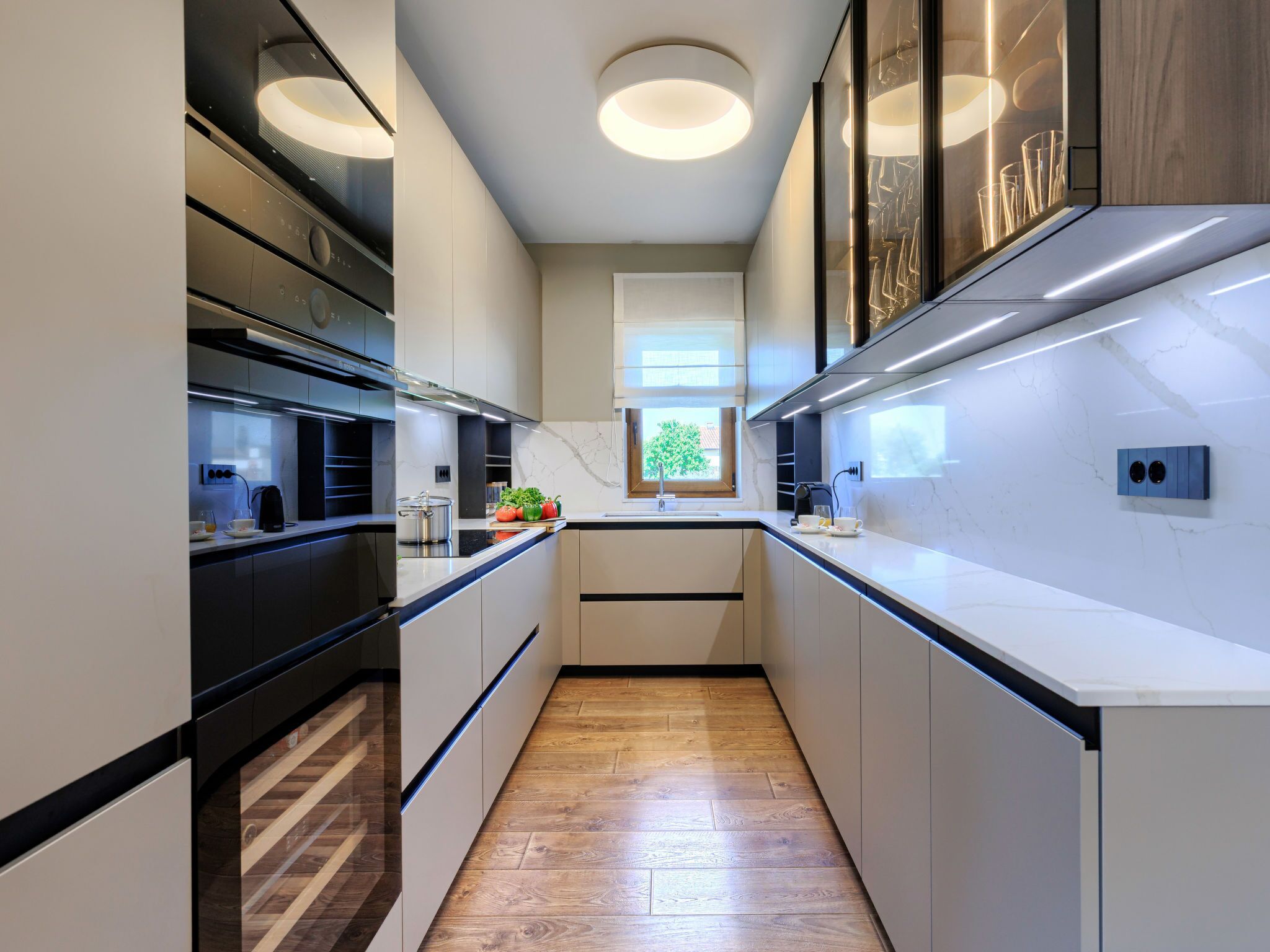 A modern kitchen with a central island, built-in appliances, and a view of the outdoors.