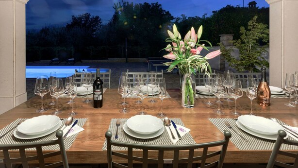 An outdoor dining area with a wooden table set for a meal, surrounded by chairs, and overlooking a swimming pool. - Vacation home Sara by Interhome (Poreč/Kaštelir)