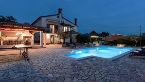 A stone-floored outdoor area with a swimming pool, lounge chairs, and a bar area. - Vacation home Sara by Interhome (Poreč/Kaštelir)