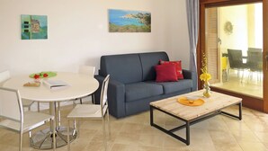 Un salon avec une table ronde, un canapé, une table basse et un tableau accroché au mur.