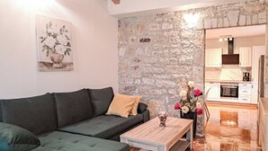 A modern living room with a green sofa, a wooden coffee table, and a stone wall. - Glavica by Interhome (Poreč)