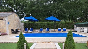 A swimming pool with blue umbrellas, lounge chairs, and a stone building. - Glavica by Interhome (Poreč)