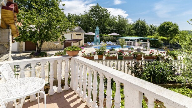 A balcony with a white railing, a small table, and potted plants. - Glavica by Interhome (Poreč)