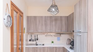 Una cocina moderna con armarios de madera, un lavamanos de acero inoxidable y una lámpara colgante.