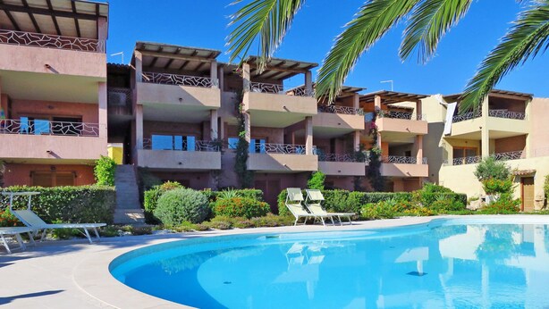 Un resort con piscina, varios balcones y palmeras.
