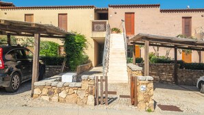 Un patio con una escalera de piedra que conduce a un edificio con tejas de arcilla y contraventanas de madera.