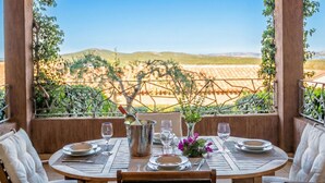 Mesa lista para comer con vista a un viñedo y colinas al fondo.