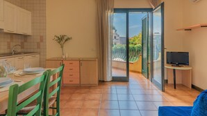 Una cocina moderna con comedor, televisor y balcón con vistas a edificios.