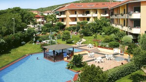 Un hotel con piscina, zona de estar al aire libre y abundante vegetación.