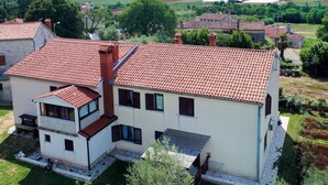 A two-story building with a red-tiled roof, a balcony, and a garden area. - Apartment Kuki by Interhome (Poreč)