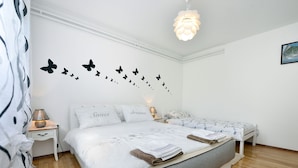 A bedroom with a bed, two bedside tables, a lamp, a wall with butterfly decals, and a hanging light fixture. - Apartment Kuki by Interhome (Poreč)