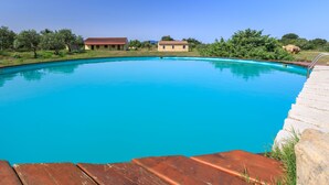 Una piscina azul cristalina rodeada por una terraza de madera y un muro de piedra.