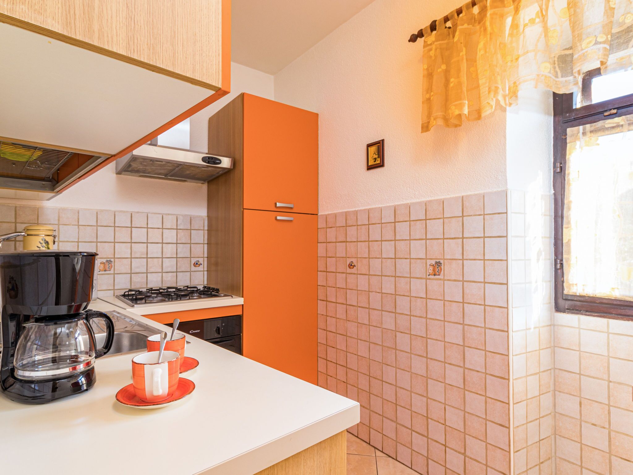 Een keuken met een fornuis, koffiezetapparaat en een spoelbak.