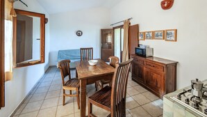 A dining area with a wooden table and chairs, a microwave, and a stove. - La Pietraia by Interhome (Badesi)