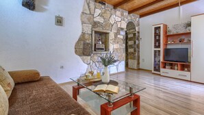 A living room with a stone fireplace, a glass coffee table, a sofa, and a TV stand. - Vacation home Kate by Interhome (Pićan)