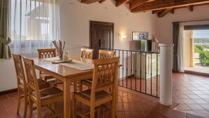 Un coin repas avec une table et des chaises en bois, une vue sur l’extérieur et un balcon doté d’une balustrade.