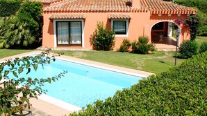 Une maison avec une piscine, entourée de verdure et sous un ciel dégagé.